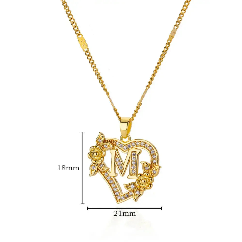Colar dourado com pingente em formato de coração decorado com letra M e flores com pedras brilhantes
