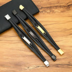 Pulseiras masculinas de couro preto com placas metálicas prateada, preta e dourada sobre superfície de madeira